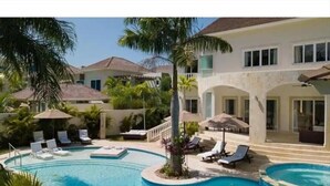 Ein Resort mit großem Poolbereich, Liegestühlen und Palmen.