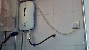 A white water heater with a control knob and a hose connected to a showerhead. - Hansonic Hotel (Accra)