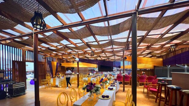 A spacious hall with long tables, golden chairs, and a high ceiling with a net-like structure. - Hansonic Hotel (Accra)