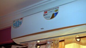 A white air conditioning unit with a TCL logo and a sticker indicating it is a split type. - Hansonic Hotel (Accra)
