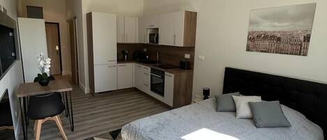 Un dormitorio moderno con una cama grande, una pequeña cocina y una mesa de comedor.
