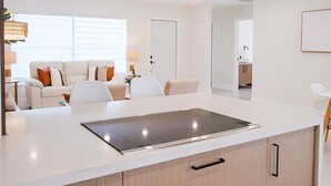 A modern kitchen with a central island, built-in cabinets, and a stainless steel range hood.
