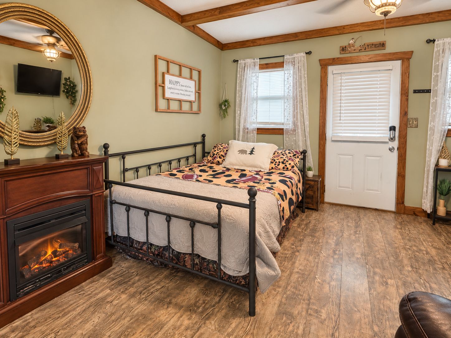 A bedroom with a bed, a fireplace, a television, and a door.