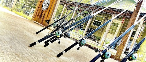 A row of fishing rods leaning against a fence.
