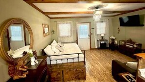 Un dormitorio con cama, cómoda, espejo, escritorio y televisor.