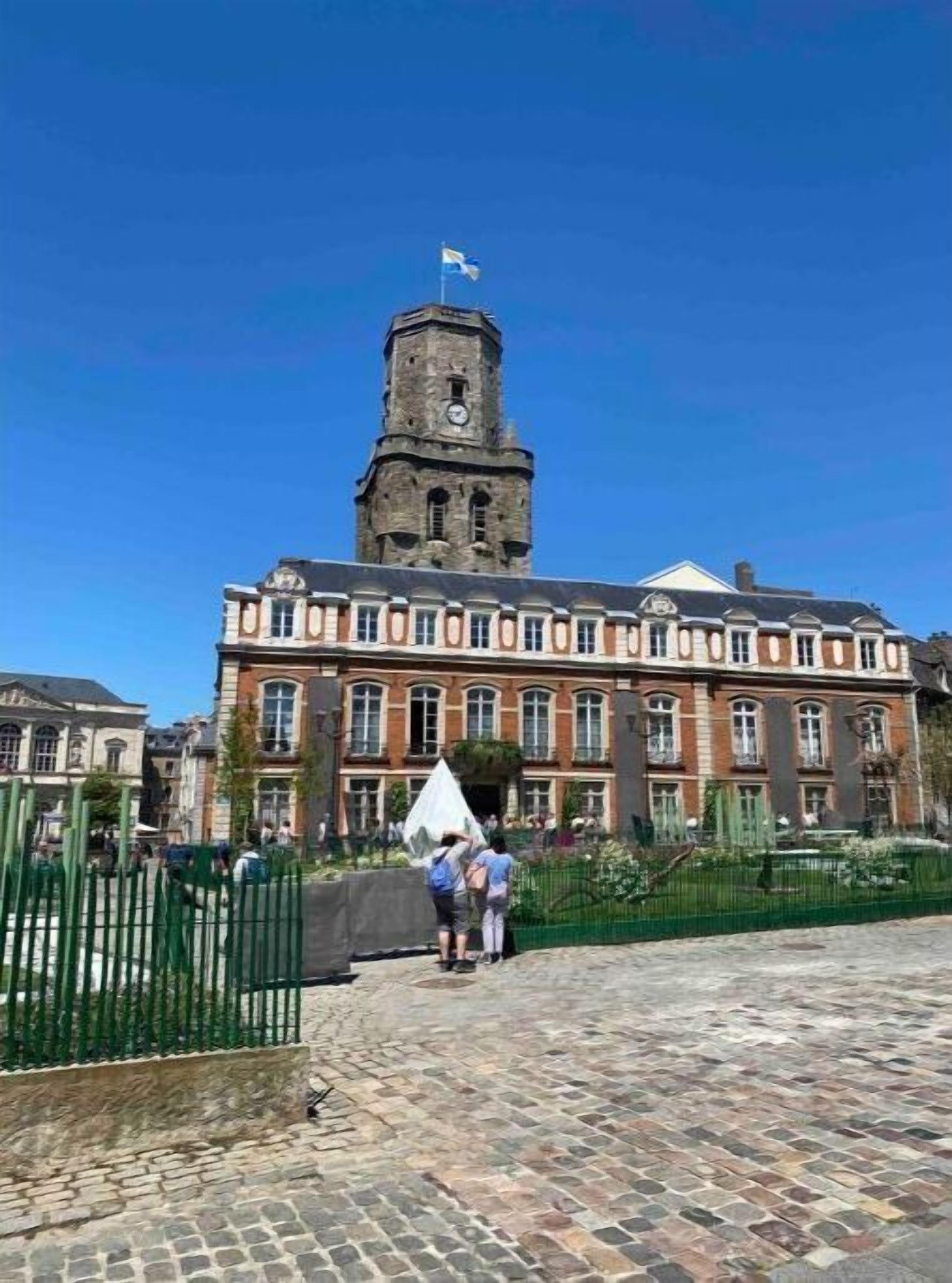 Un edificio histórico con una imponente torre de reloj y una amplia entrada principal.