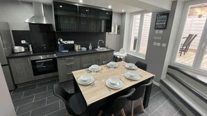Una cocina moderna con comedor, muebles grises y vistas al exterior.