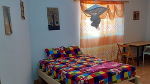 Ein Schlafzimmer mit einem Holzbett, einem Schreibtisch und einem Deckenventilator.