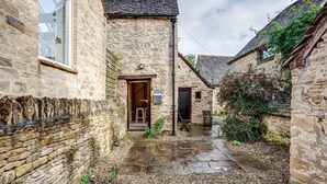 A narrow stone courtyard with a wooden door, a small table, and a bench.