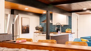 A modern kitchen with a central island, white cabinets, and a blue backsplash.