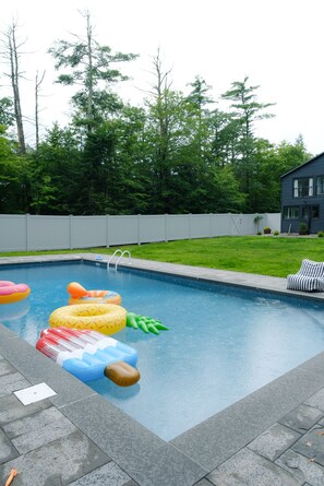 Relax by the pool surrounded by lush greenery and a beautiful view of the house.