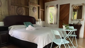 A bedroom with a bed, a nightstand, a table with chairs, a sink, and decorative plates on the wall. - El Zota Hotel (Rita)
