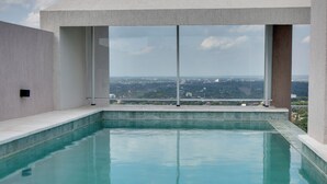 Una piscina infinita moderna con vistas despejadas del paisaje urbano a través de amplios ventanales.