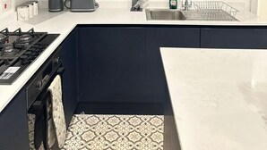 Una cocina moderna con armarios oscuros, encimera blanca y salpicadero con estampado.