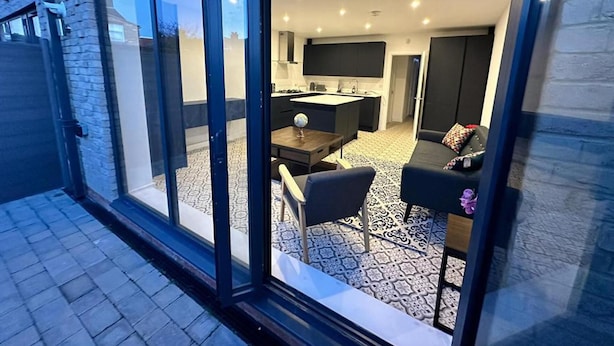 Una cocina moderna con una isla central, una zona de comedor con mesa y sillas, y un suelo estampado.
