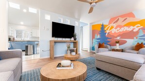 A modern living room with a flat-screen TV, a round coffee table, and a sofa. - Walk to Beach HotTub FirePit Game room Lake View (East Stroudsburg)