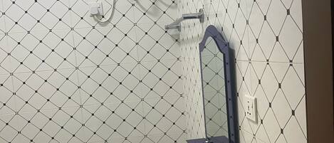 A bathroom with a white sink, a mirror, and a shower with a water heater.
