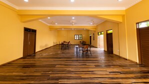 A spacious hall with wooden flooring, yellow walls, and multiple doors. - Akpe Cultural Center and Hotel (Accra)