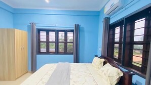 A bedroom with a bed, a wardrobe, a ceiling fan, and a window with curtains. - Akpe Cultural Center and Hotel (Accra)