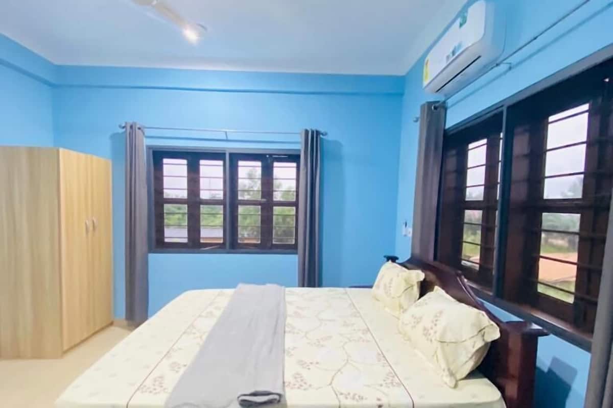 A bedroom with a bed, a wardrobe, a ceiling fan, and a window with curtains.