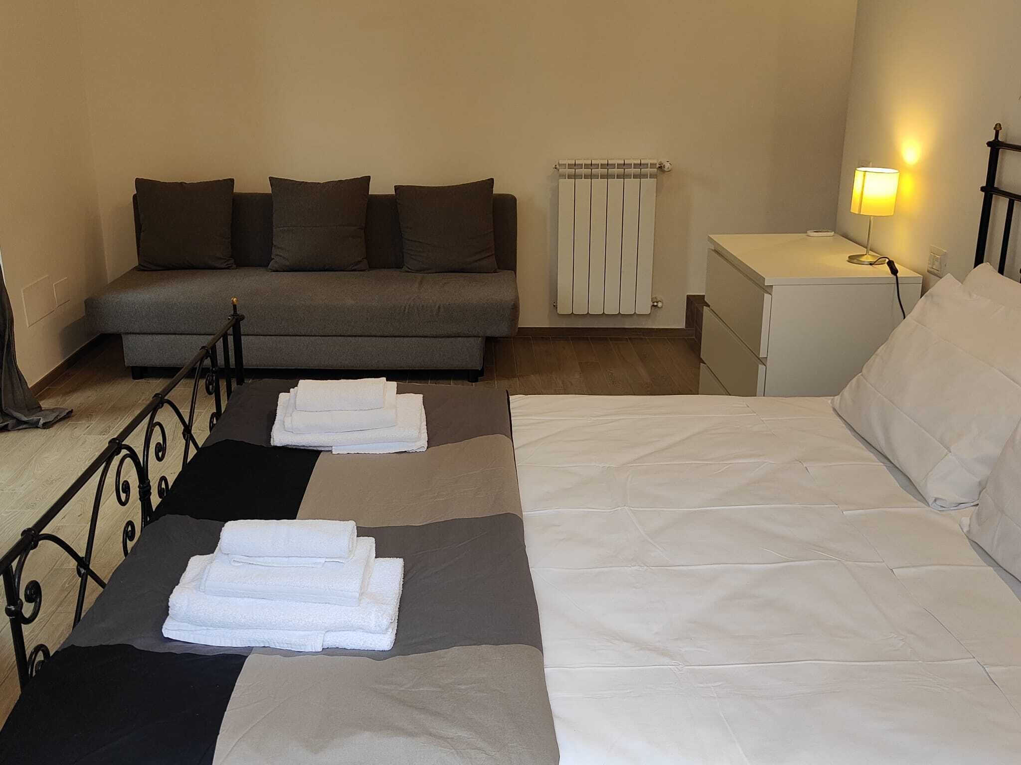 Une chambre à coucher avec un lit, un canapé, une table de chevet et une lampe.