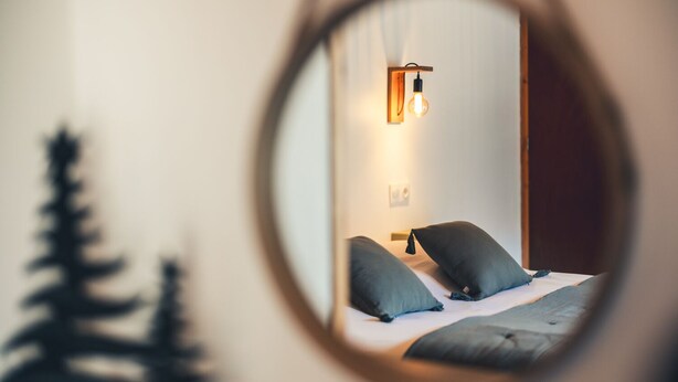 Una camera da letto con un letto, cuscini, un comodino e una lampada a parete.