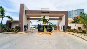 A hotel entrance with a modern design, featuring a prominent sign and a gated driveway.