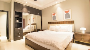 A modern bedroom with a large bed, dark wooden wardrobe, and bedside tables. - LnD Villa! Lovely gated community, 24 hrs security, amazing view, and pool  (Ocho Rios)
