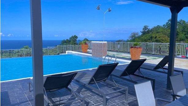 A poolside area with lounge chairs and a view of the ocean. - LnD Villa! Lovely gated community, 24 hrs security, amazing view, and pool  (Ocho Rios)