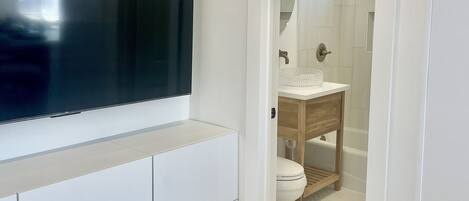 A modern bathroom with a large mirror, a sink, and a toilet.