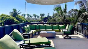 Un espace de détente aménagé sur le toit, avec des sièges confortables dotés de coussins verts et un grand auvent.