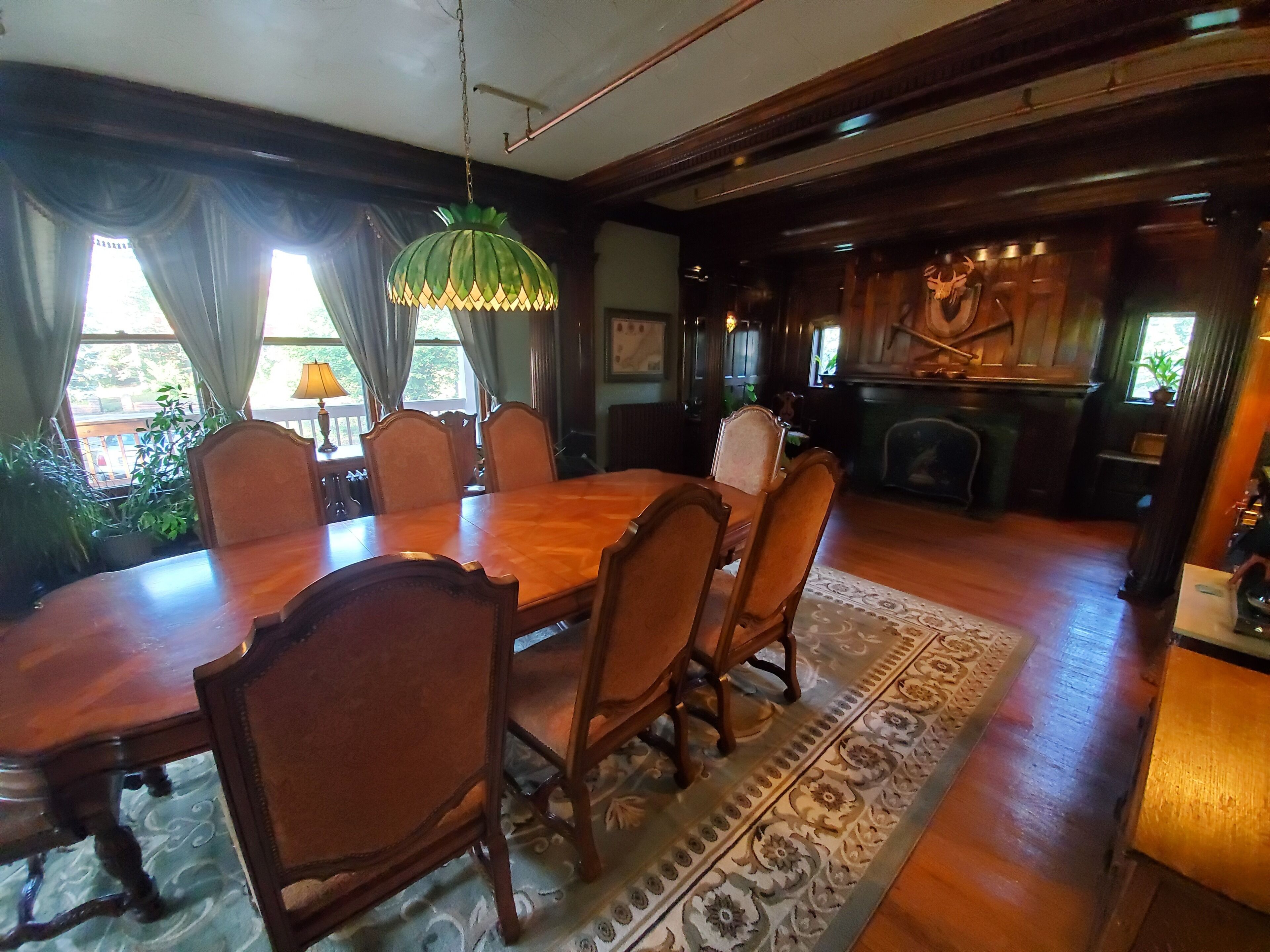 A dining room with a wooden table and chairs, a patterned rug, and a hanging light fixture.