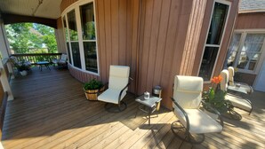 A wooden deck with two white chairs, a small table, and a potted plant. - Deluxe Queen with Park View (Laurium)