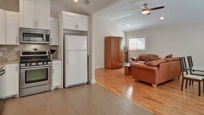 A modern kitchen with white cabinets, stainless steel appliances, and a wooden dining area with a sofa and chairs.