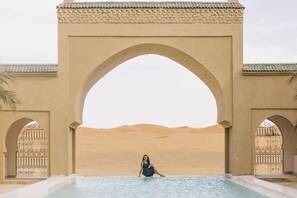 Zona de piscina con una entrada arqueada y vistas al desierto.
