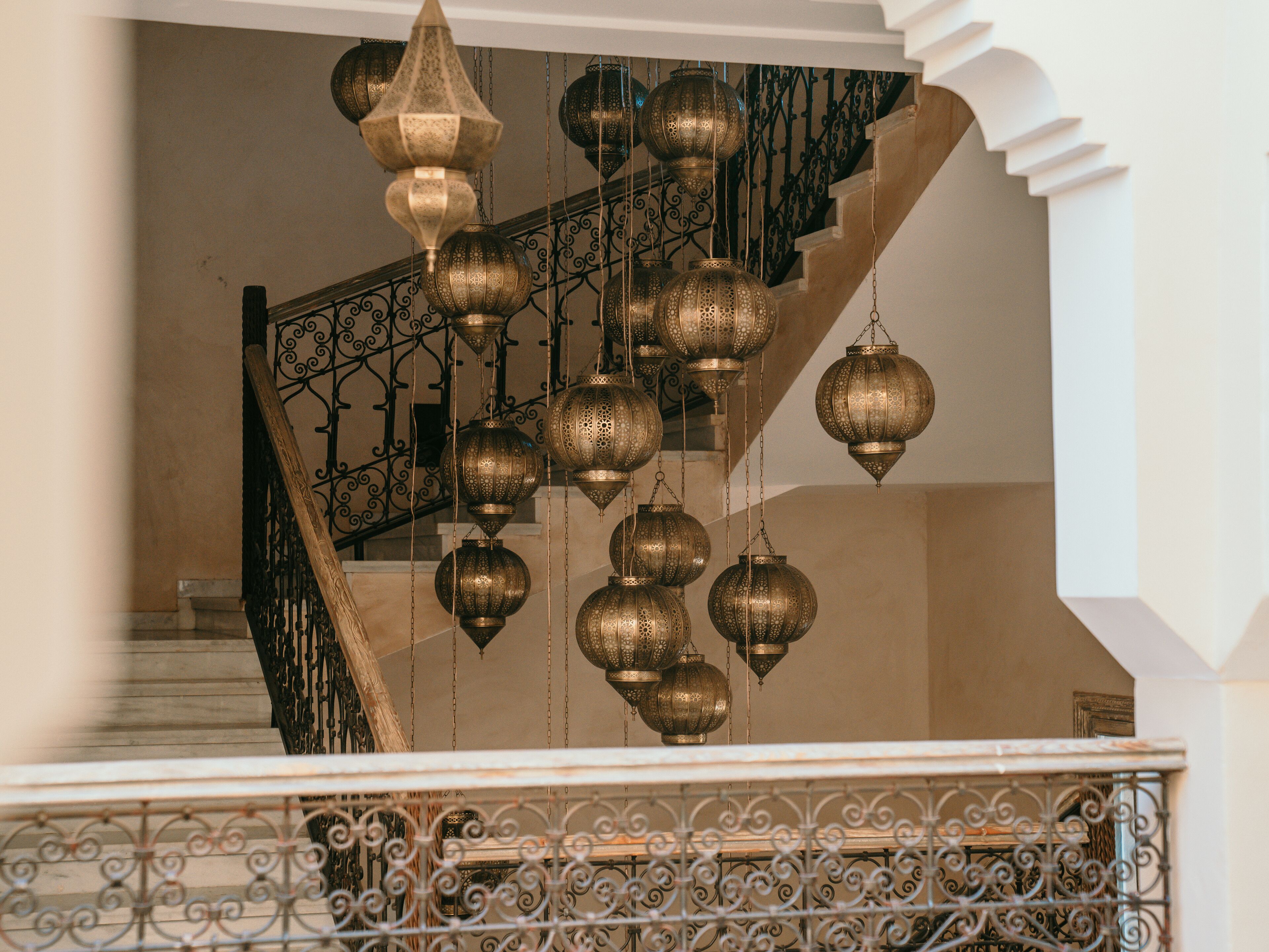 Una escalera con barandillas de metal decoradas y faroles colgantes.