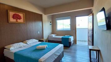 Une chambre d’hôtel avec un grand lit, un lit plus petit, une télévision et une fenêtre.