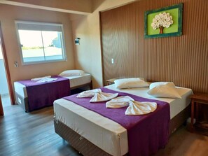 A hotel room with two beds, a window, a wall-mounted picture, and a wooden floor. - Do Parque Pousada Comfort (Penha)