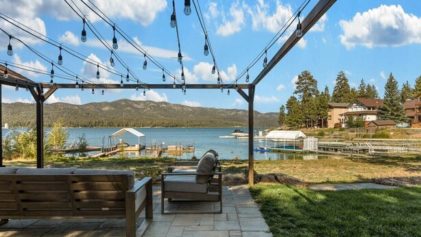 Un espace extérieur abrité, aménagé avec des sièges, et offrant une vue sur un lac et des montagnes.