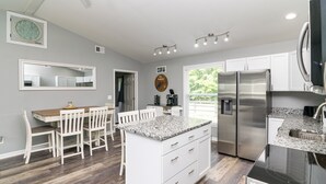 A modern kitchen with white cabinetry, a granite countertop, stainless steel appliances, and a dining area with white chairs and a wooden table. - Cozy Lake Cumberland Retreat with hot tub, just above Jamestown Marina!


 (Jamestown)
