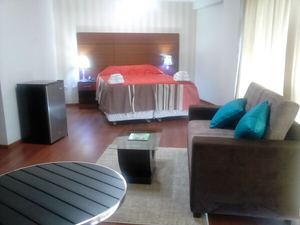 A hotel room with a bed, a sofa, a coffee table, a TV, and a speaker. - HOTEL MURCIA AREQUIPA (Arequipa)