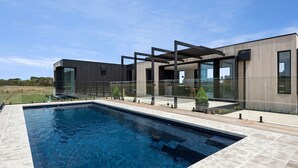 Una casa moderna con piscina, ventanas amplias y cielo despejado.