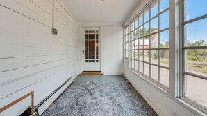 Un pasillo con paredes de madera blanca, alfombra gris y un ventanal con vistas al exterior.