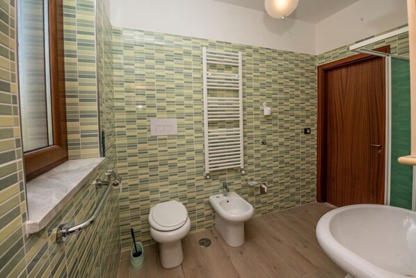 Une salle de bain équipée de toilettes, d’un bidet et d’une baignoire.