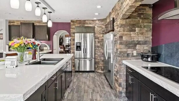A modern kitchen with a central island, stainless steel appliances, and a stone accent wall. - Experience Scottsbluff charm in our spacious 4-bedroom retreat (Scottsbluff)