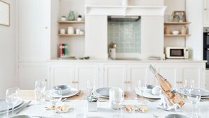 Una cocina moderna y bien iluminada, con armarios blancos, una isla central y un comedor listo para una comida.