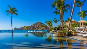 A resort pool with clear water, palm trees, and a mountain in the background. - Hacienda Beach Club, Beachfront, 5-Star, Luxury (Cabo San Lucas)