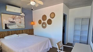 Ein Schlafzimmer mit Bett, Schreibtisch, Stuhl, Deckenventilator, Wanddekoration und Klimaanlage.