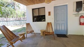Une pièce avec trois chaises en bois, une fenêtre, une porte bleue et un extincteur fixé au mur.
