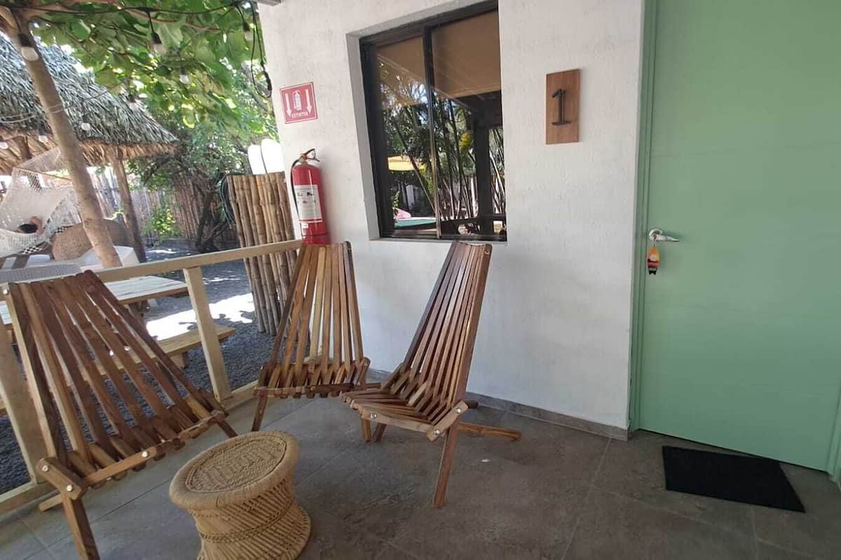 A room with a green door, a window, and two wooden chairs.